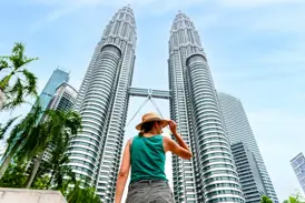 Junge Reisende in Kuala Lumpur bewundert die beeindruckende Architektur der berühmten Petronas Towers aus der Froschperspektive.