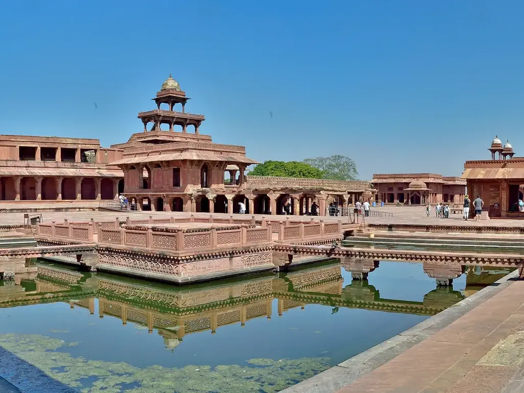 Die Palastanlage Fatehpur Sikri, UNESCO-Welterbe, mit dem roten Pavillon im Wasserbecken wird von Besuchern erkundet.