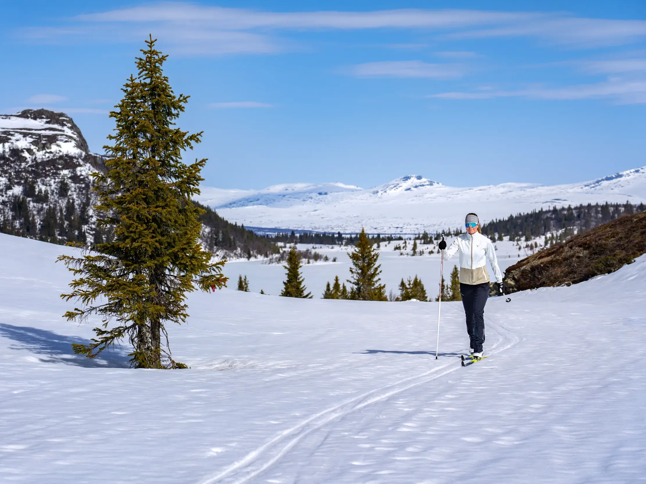 Eine Langläuferin gleitet auf Skiern durch die verschneite Winterlandschaft von Valdres mit Panoramablick auf Jotunheimen.