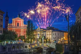 Festliches Silvesterfeuerwerk über den erleuchteten Drei Brücken und der malerischen Altstadt von Ljubljana bei Nacht.