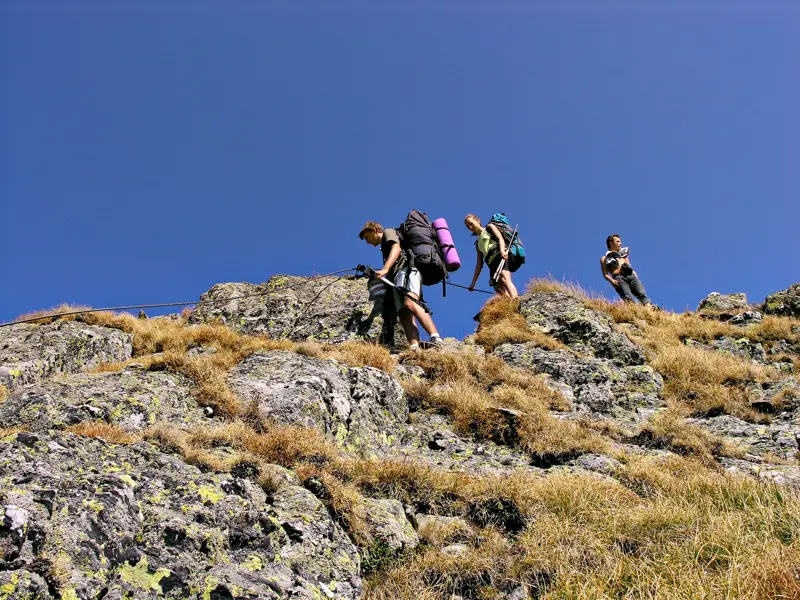 Eine kleine Trekkinggruppe überquert einen seilgesicherten Felsgrat im Fagaras Gebirge in den rumänischen Karpaten.