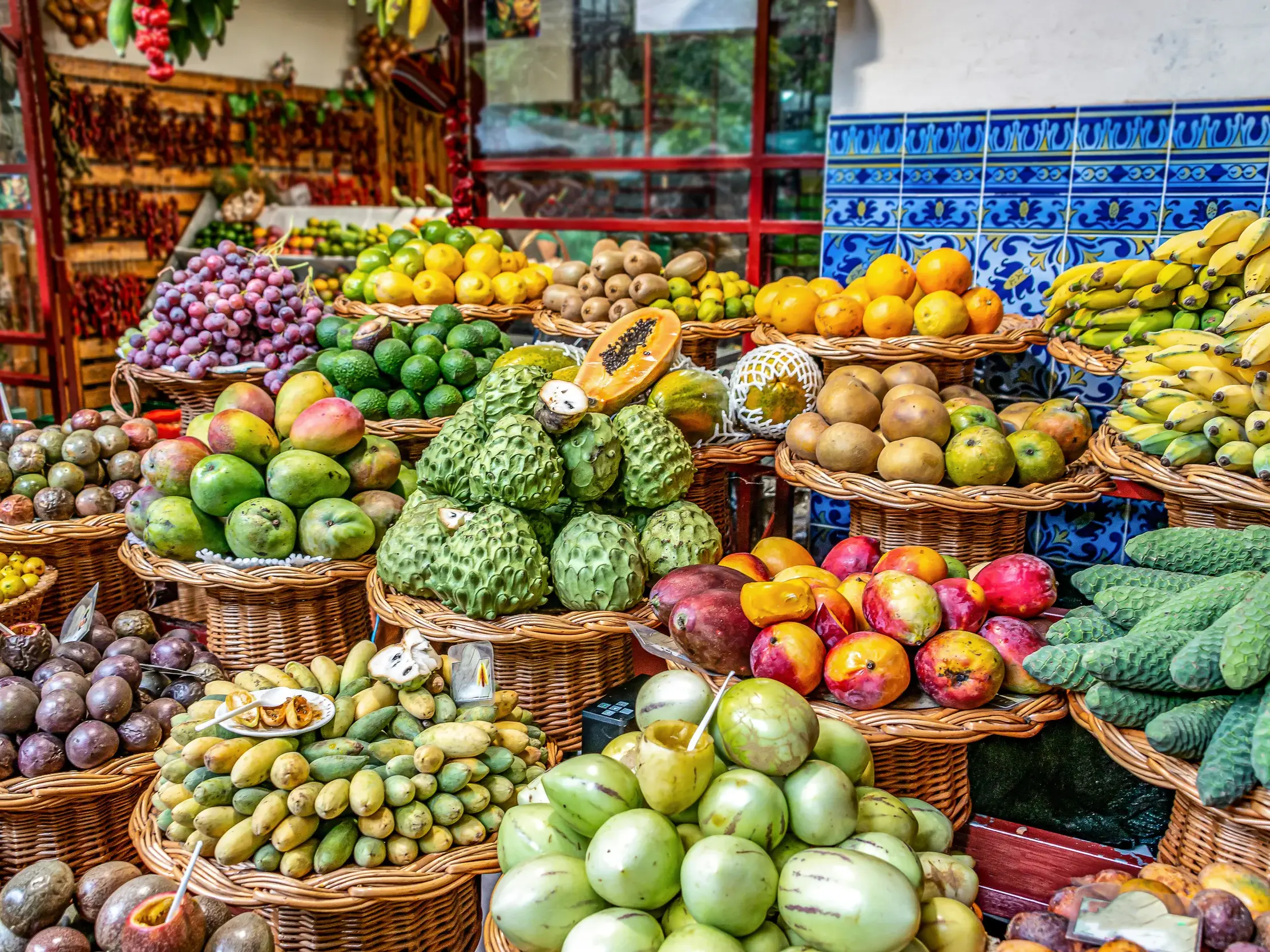 Üppig gefüllte Weidenkörbe mit einer bunten Vielfalt exotischer Früchte auf dem Mercado dos Lavradores in Funchal.