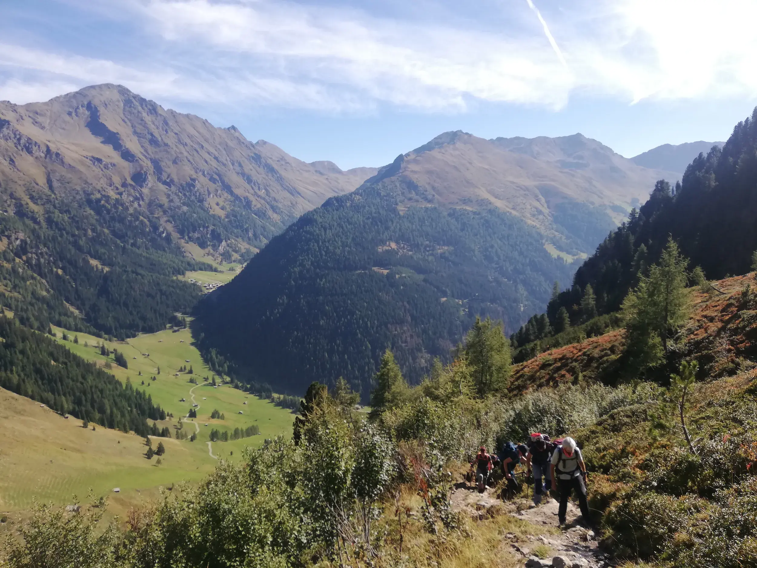 Wandergruppe auf einem schmalen Bergpfad in Osttirol mit weitem Ausblick über das sonnige Villgratental und die Berge.