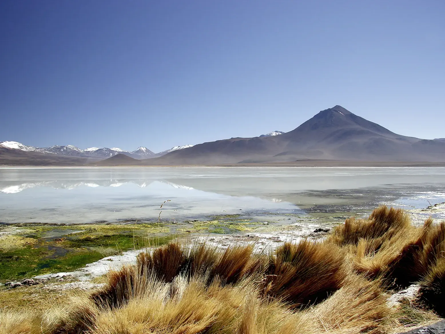 Der Vulkan Licancabur spiegelt sich in der Laguna Verde im Altiplano Boliviens, umgeben von schneebedeckten Andengipfeln.