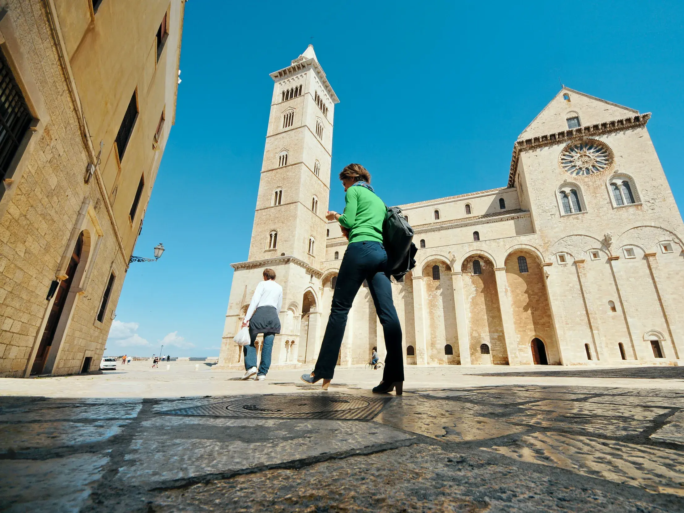 Zwei Frauen einer Studiosus-Reise auf dem Platz vor der imposanten Kathedrale von Trani in Apulien, direkt am Meer.