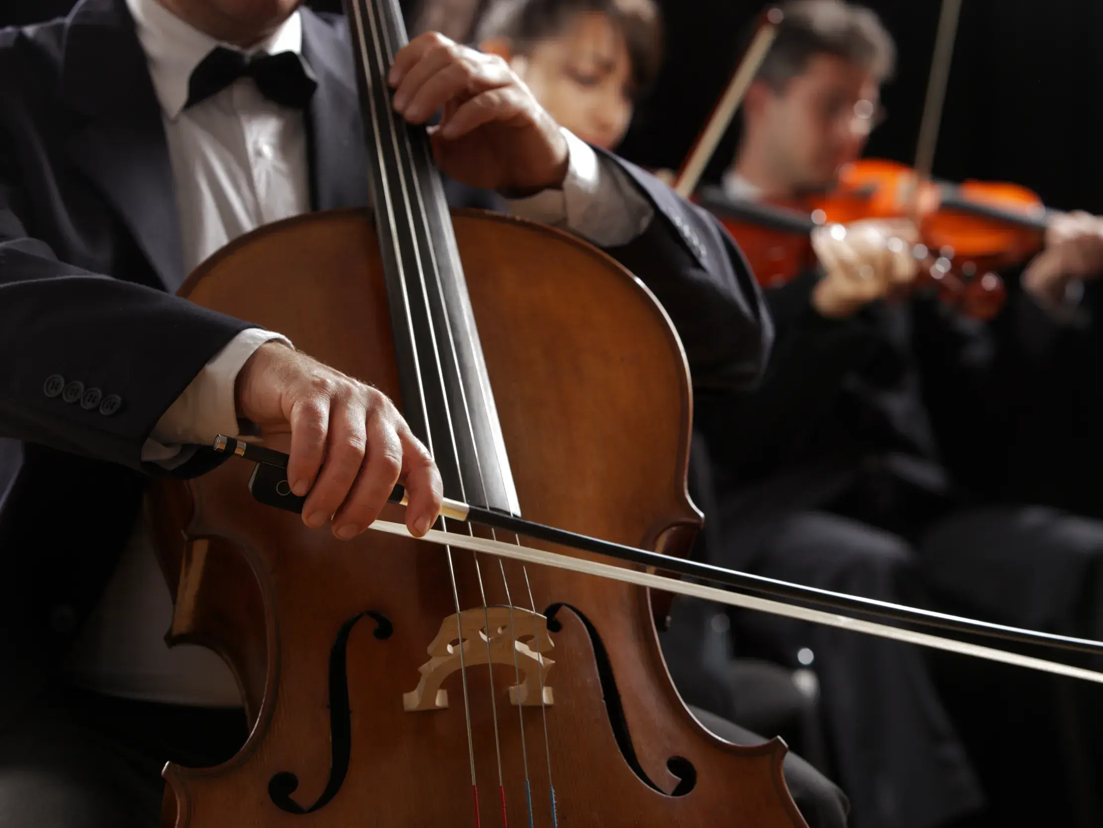 Cellist und Geiger bei einem klassischen Konzert im Orchester für eine Opernaufführung.