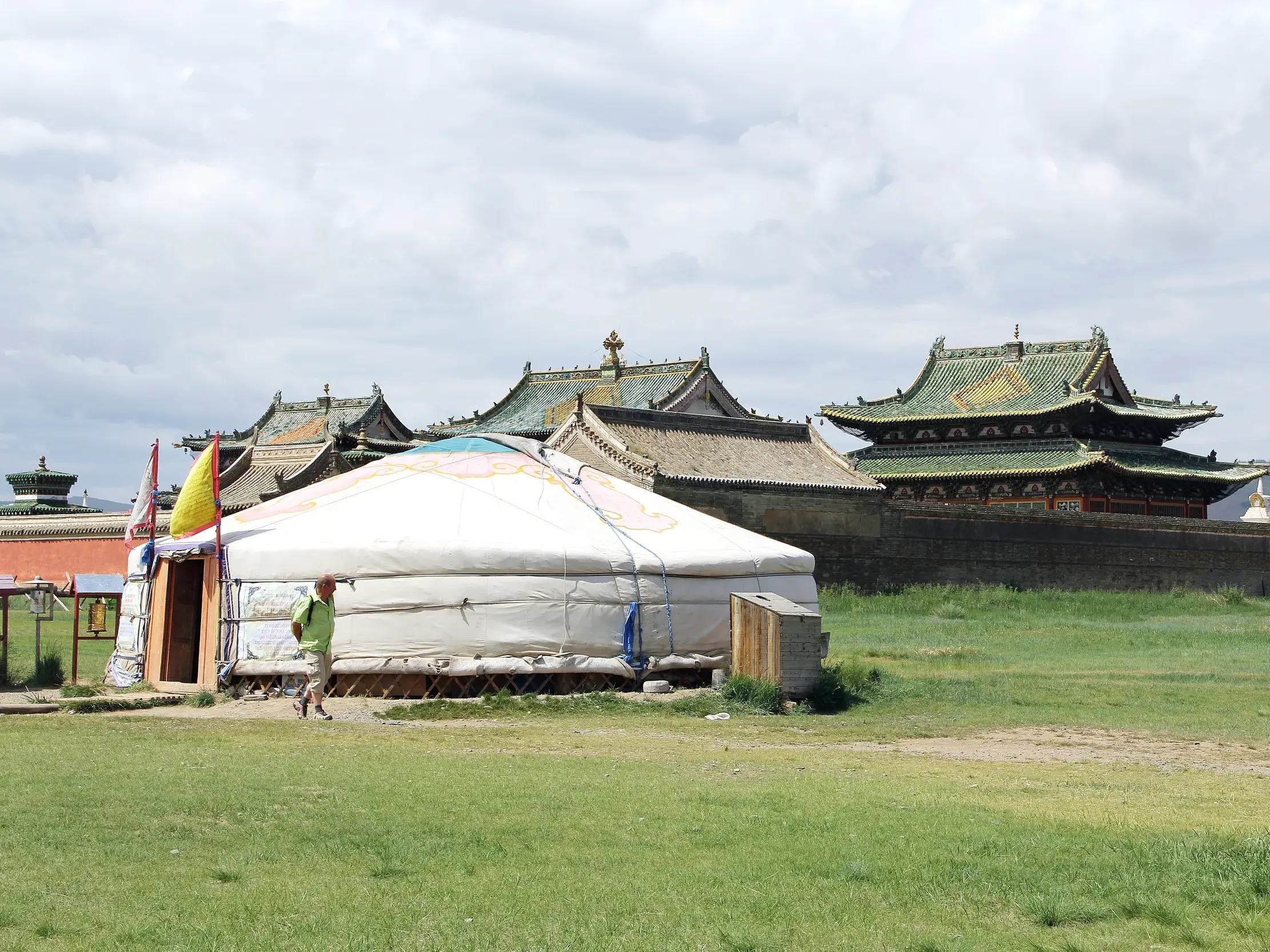 Eine traditionelle, weiße Jurte auf einer Wiese vor der historischen Tempelanlage des Klosters Erdene Zuu in Karakorum.