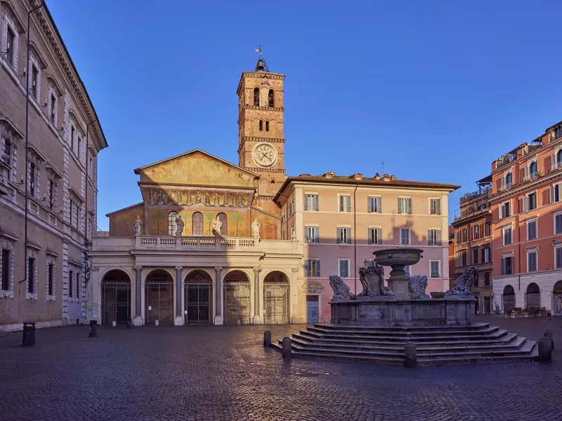 Die Basilika Santa Maria in Trastevere auf dem menschenleeren, sonnigen Platz in Rom am Ende der Hauser Trekkingreise.
