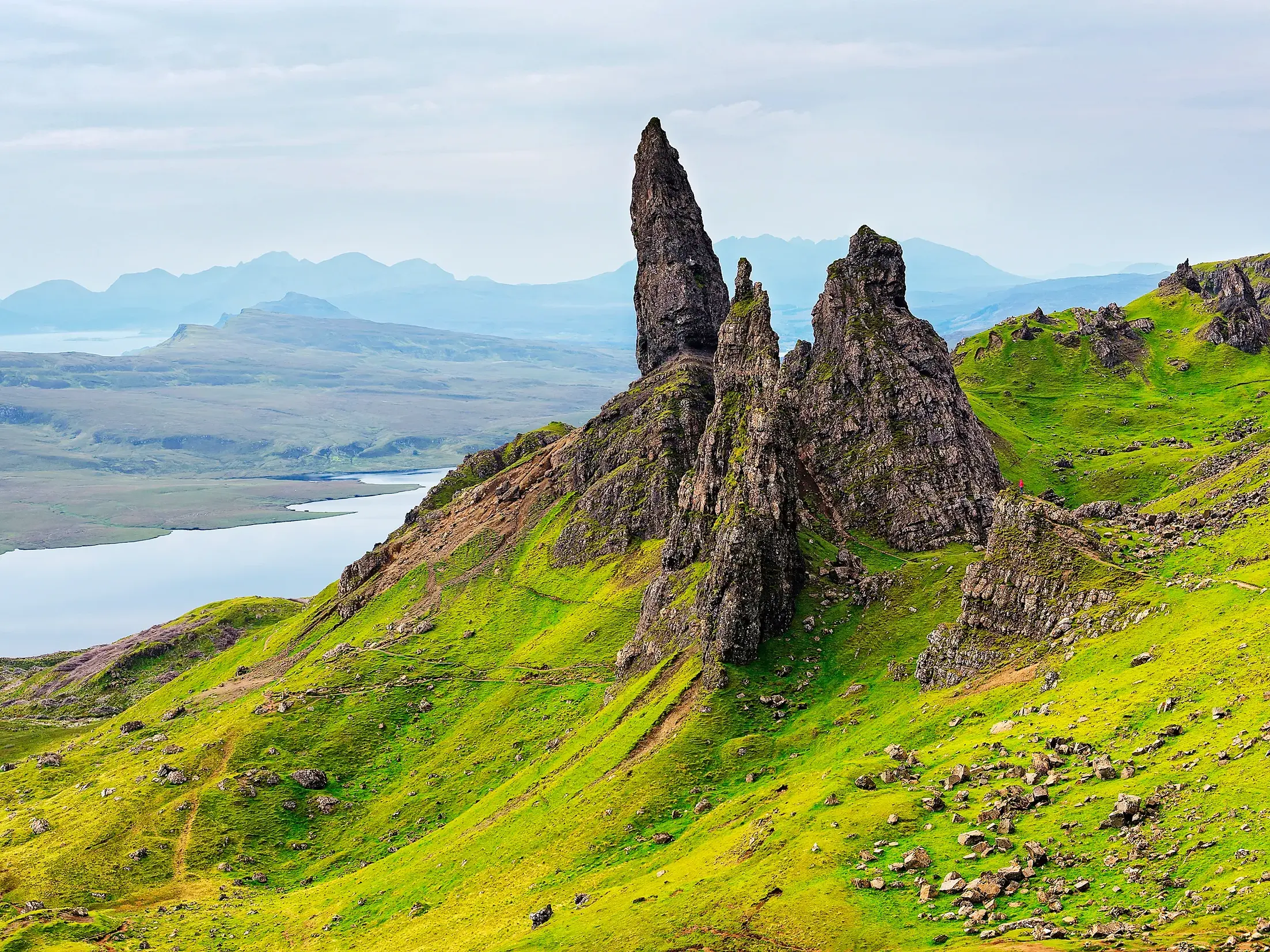 Die Felsnadel Old Man of Storr auf der Trotternish-Halbinsel ragt aus der grünen Landschaft der Isle of Skye empor.