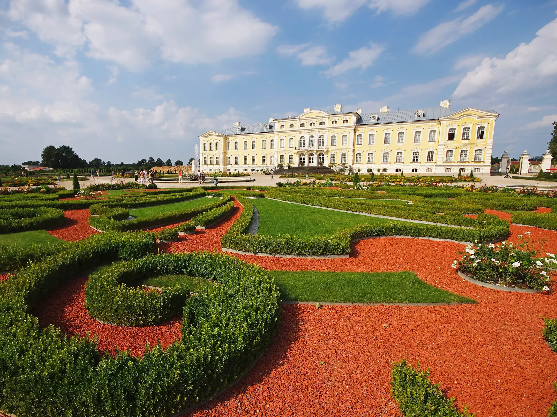 Das barocke Schloss Rundale in Lettland mit seinem berühmten Garten, gestaltet mit kunstvollen Heckenornamenten und rotem Schotter.
