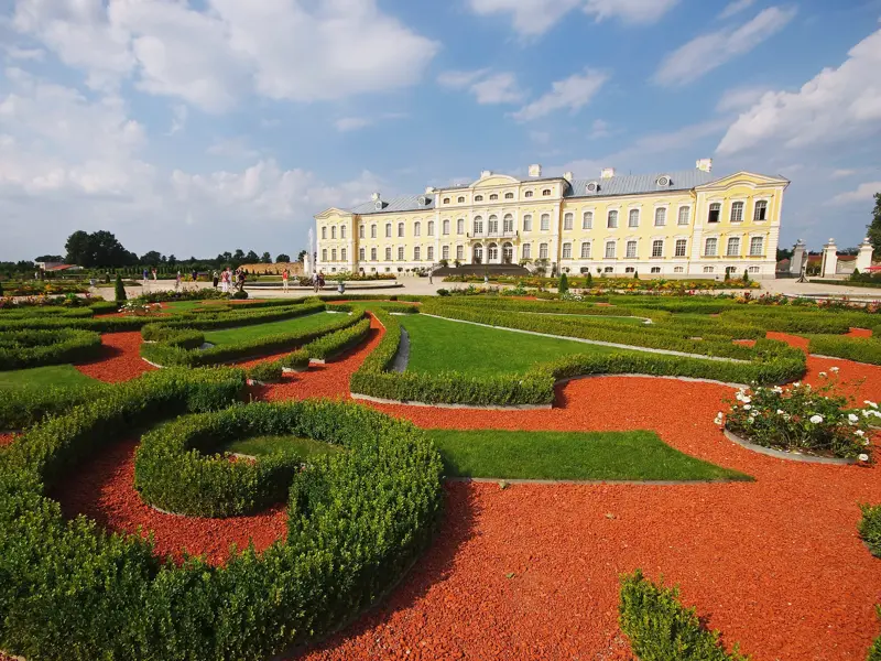 Das barocke Schloss Rundale in Lettland mit seinem berühmten Garten, gestaltet mit kunstvollen Heckenornamenten und rotem Schotter.
