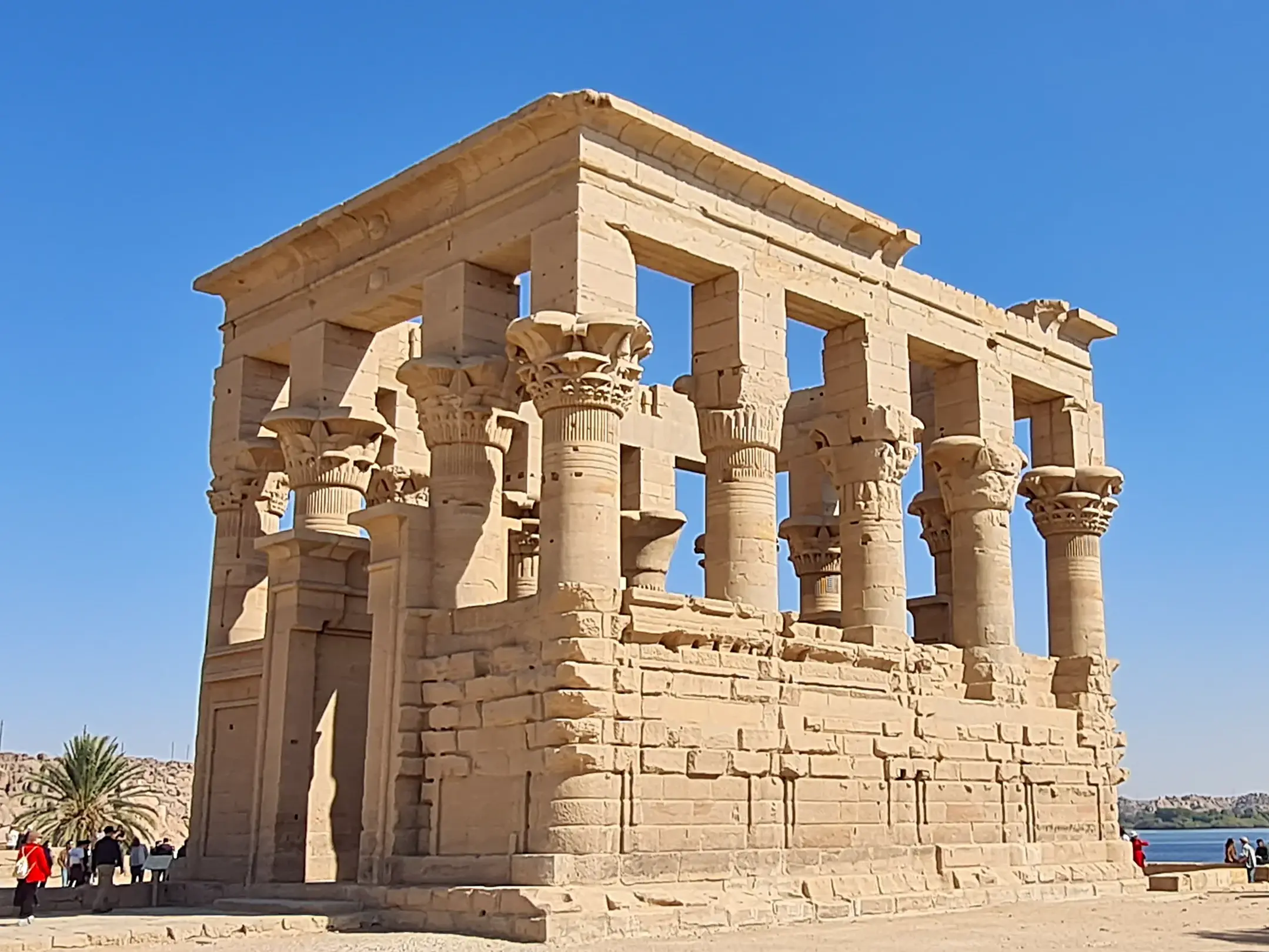 Der antike Trajan-Kiosk auf der Tempelinsel Philae bei Assuan wird von einer Reisegruppe bei Sonnenschein besichtigt.