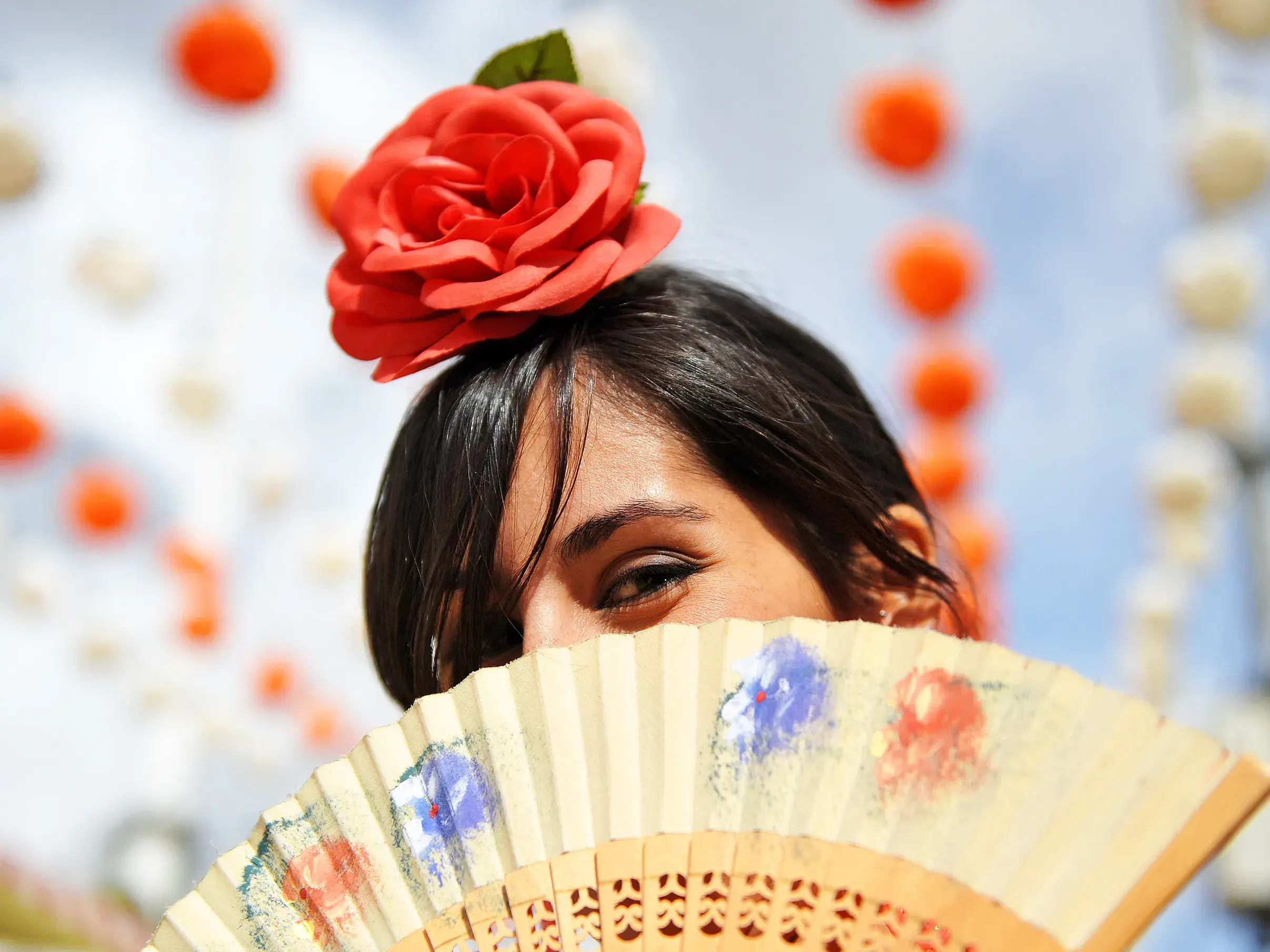 Frau mit roter Rose im Haar und Fächer bei einem traditionellen andalusischen Fest