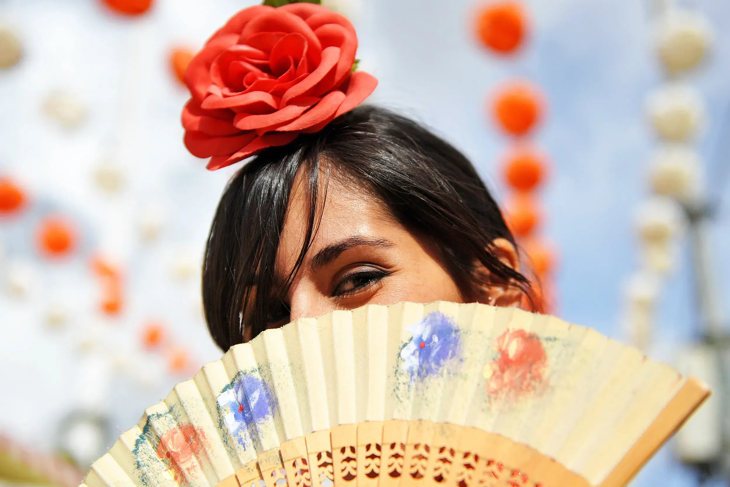 Frau mit roter Rose im Haar und Fächer bei einem traditionellen andalusischen Fest