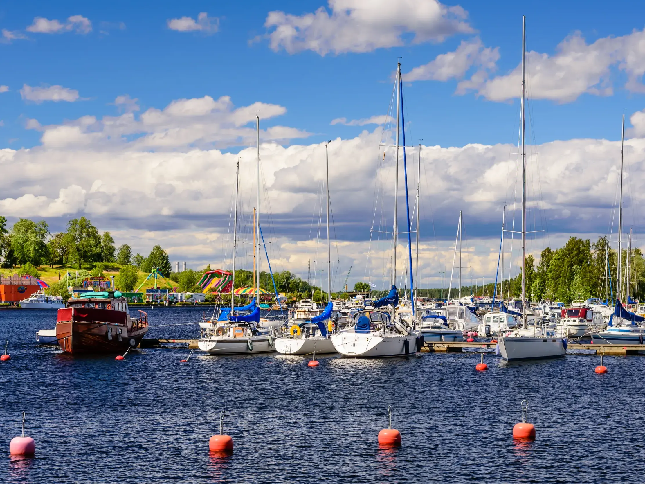 Zahlreiche Segelboote im Hafen von Lappeenranta am Saimaa-See, im Hintergrund die grüne Uferlandschaft Finnlands.