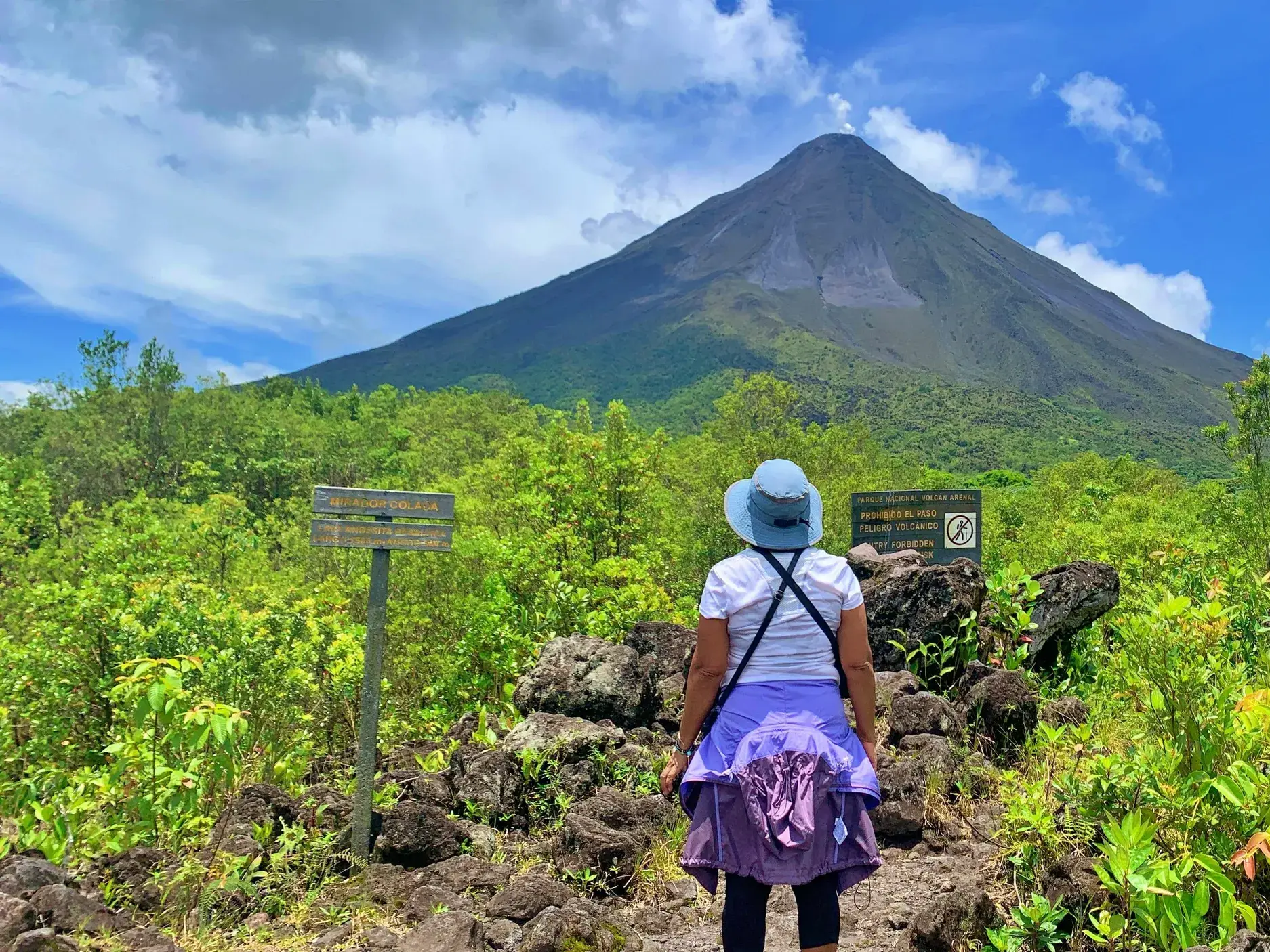 Hauser-Reisende auf einem Wanderweg durch den Regenwald mit beeindruckendem Blick auf den Vulkan Arenal in Costa Rica.
