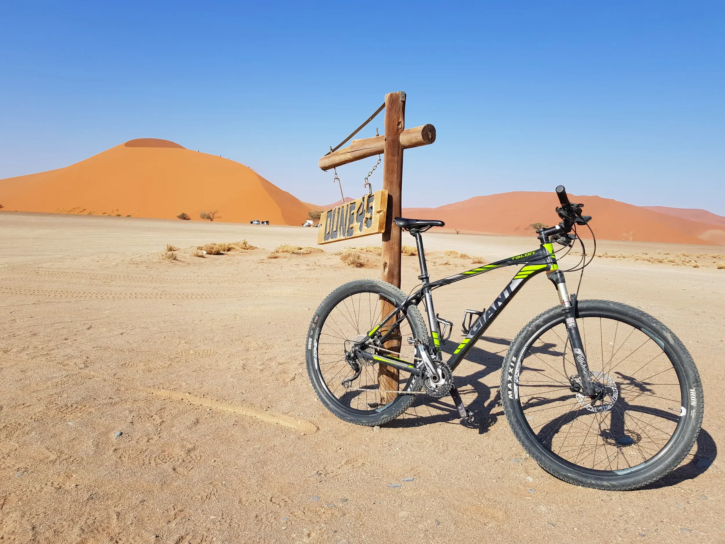 Geparktes Mountainbike am Wegweiser zur Düne 45 in der weiten Sandlandschaft der Namib-Wüste in Namibia.