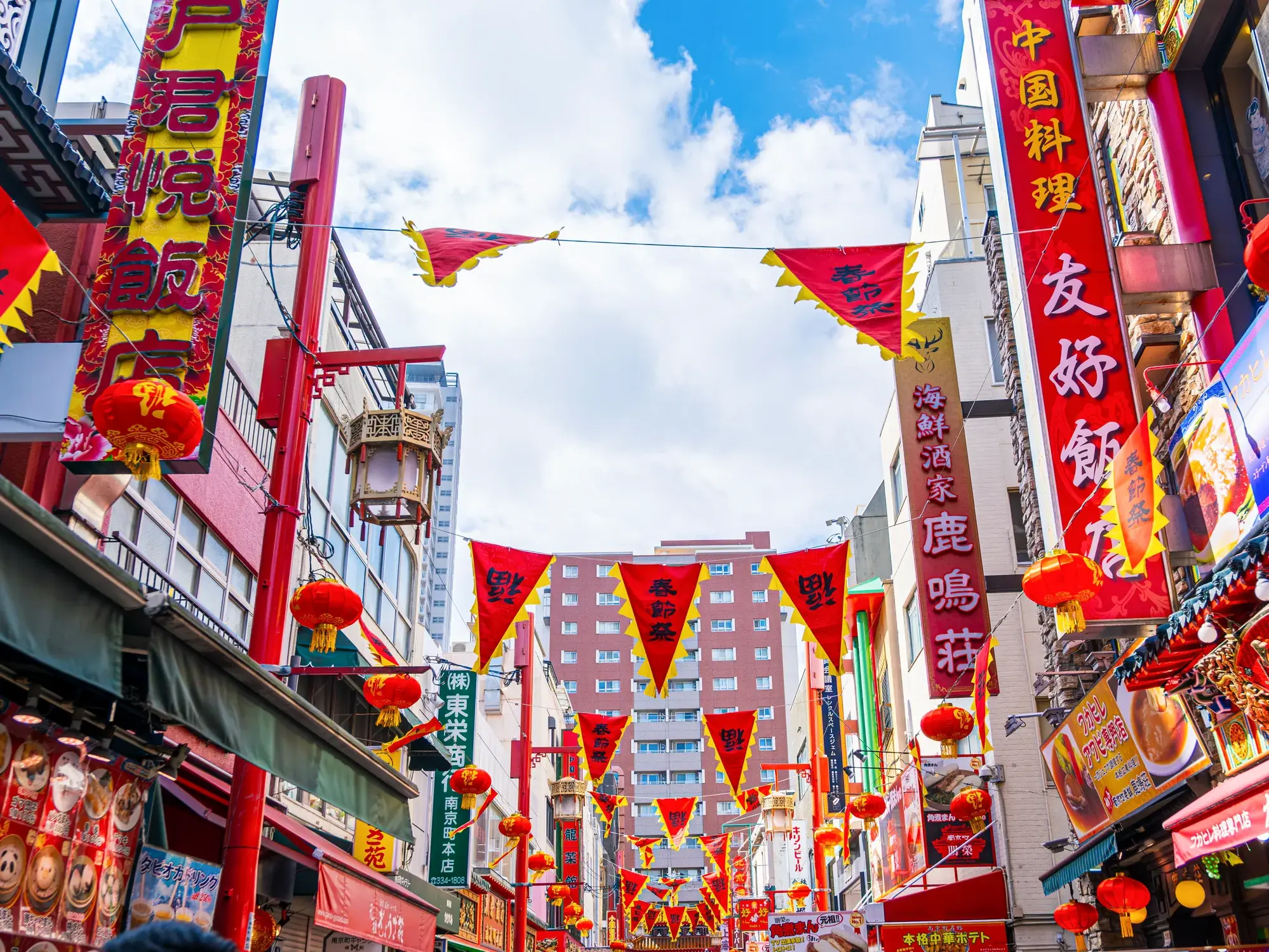 Farbenfrohe Straße in Kobes Chinatown Nankinmachi, geschmückt mit roten Lampions und Bannern mit Schriftzeichen.