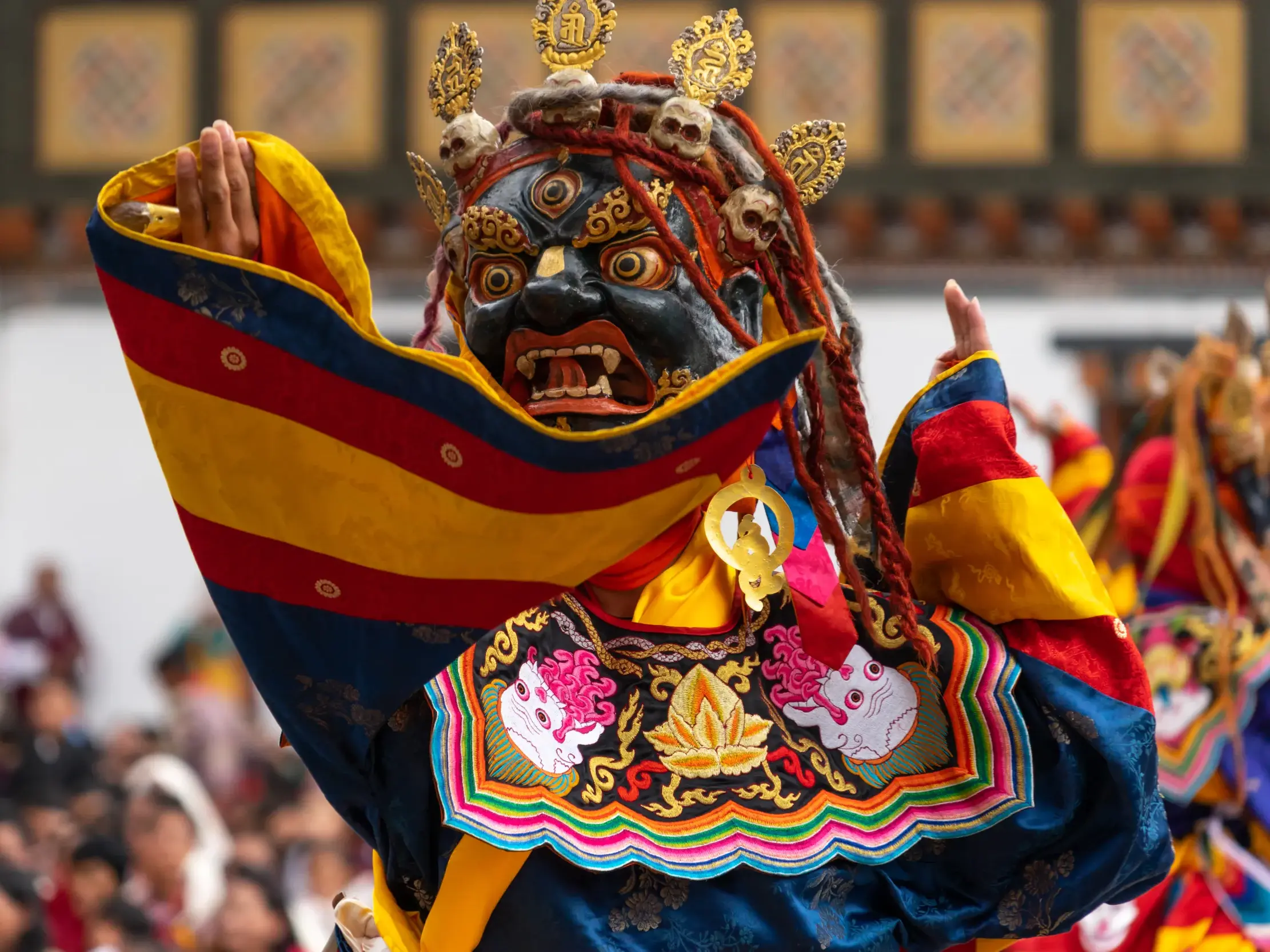 Maskentänzer in farbenprächtigem Kostüm und Dämonenmaske beim traditionellen Klosterfest Tshechu in Thimphu, Bhutan.