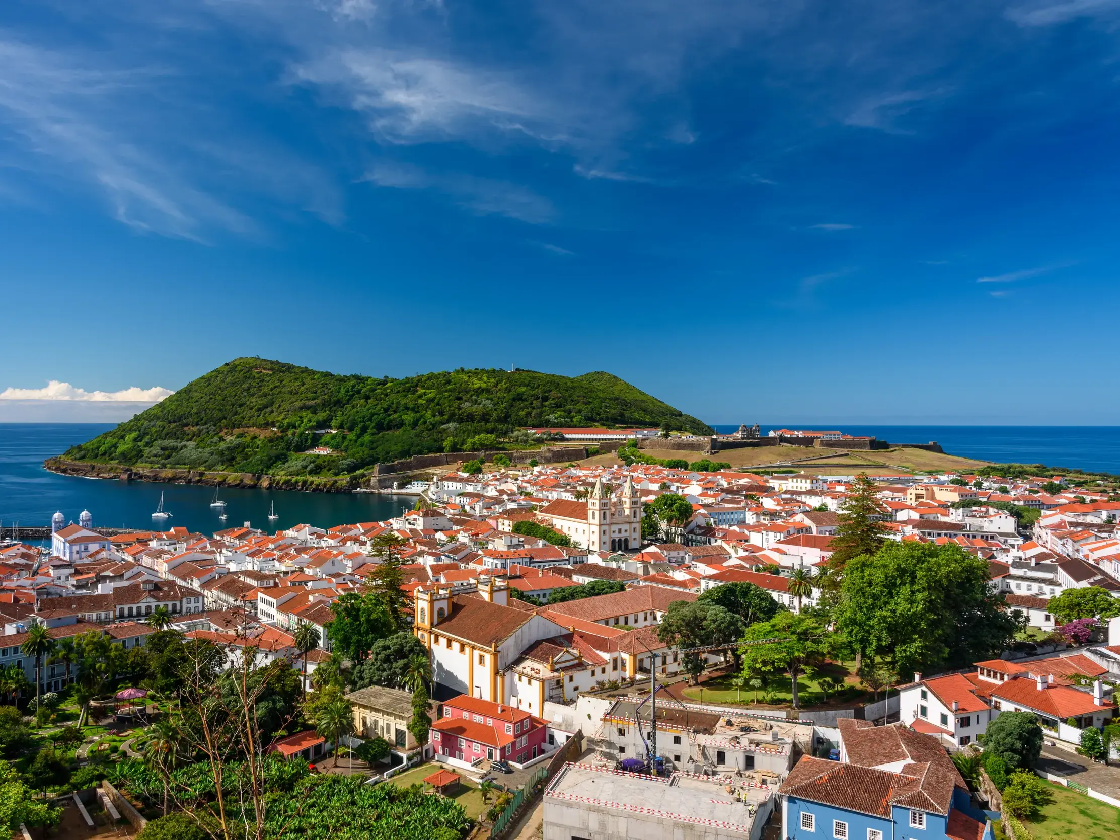 Panoramablick über die Dächer der UNESCO-Stadt Angra do Heroísmo auf Terceira, die Bucht und den bewaldeten Monte Brasil.