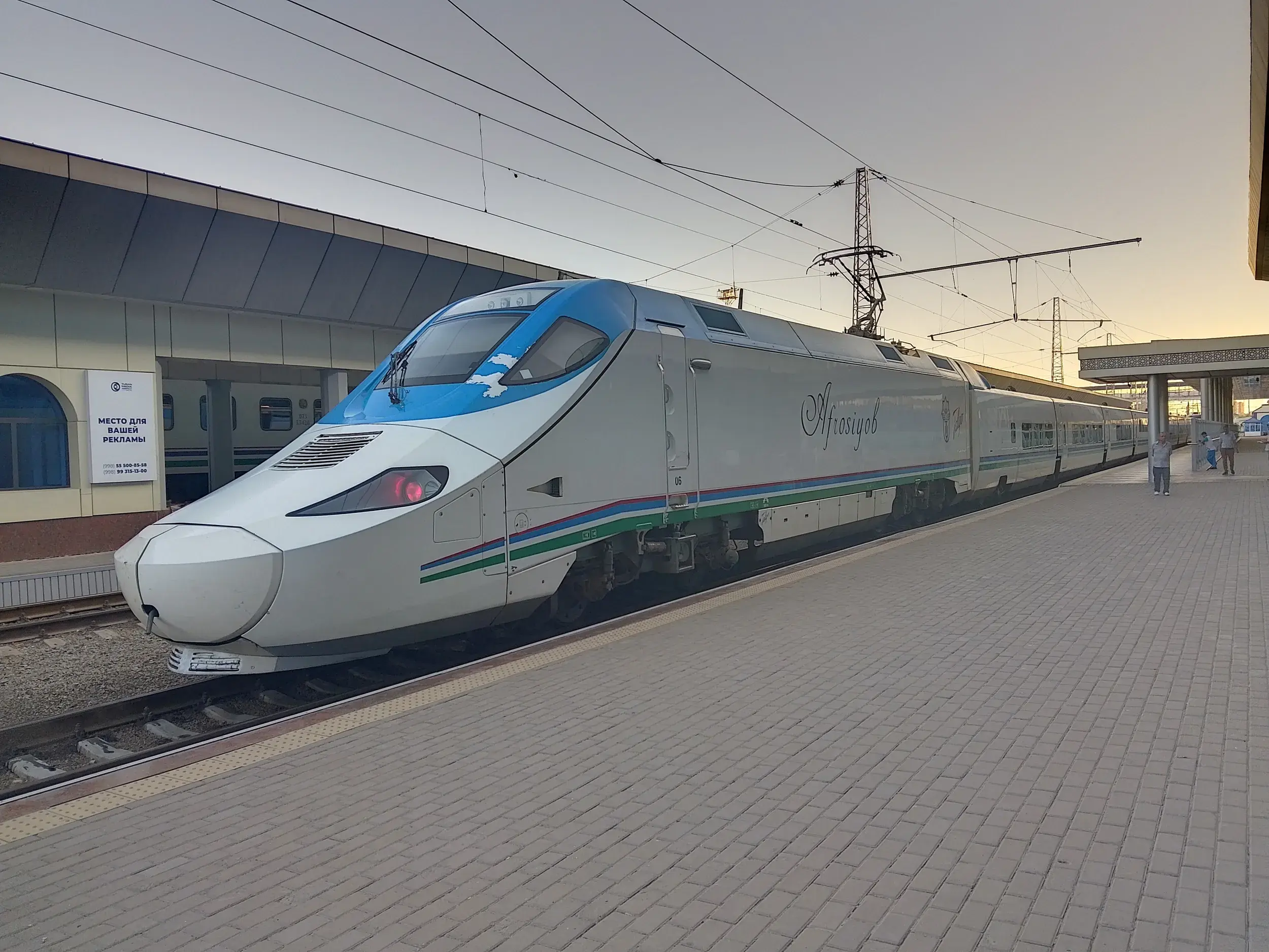 Der weiß-blaue Schnellzug Afrosiyob steht im Abendlicht an einem Bahnhof in Usbekistan für die Weiterreise nach Buchara.