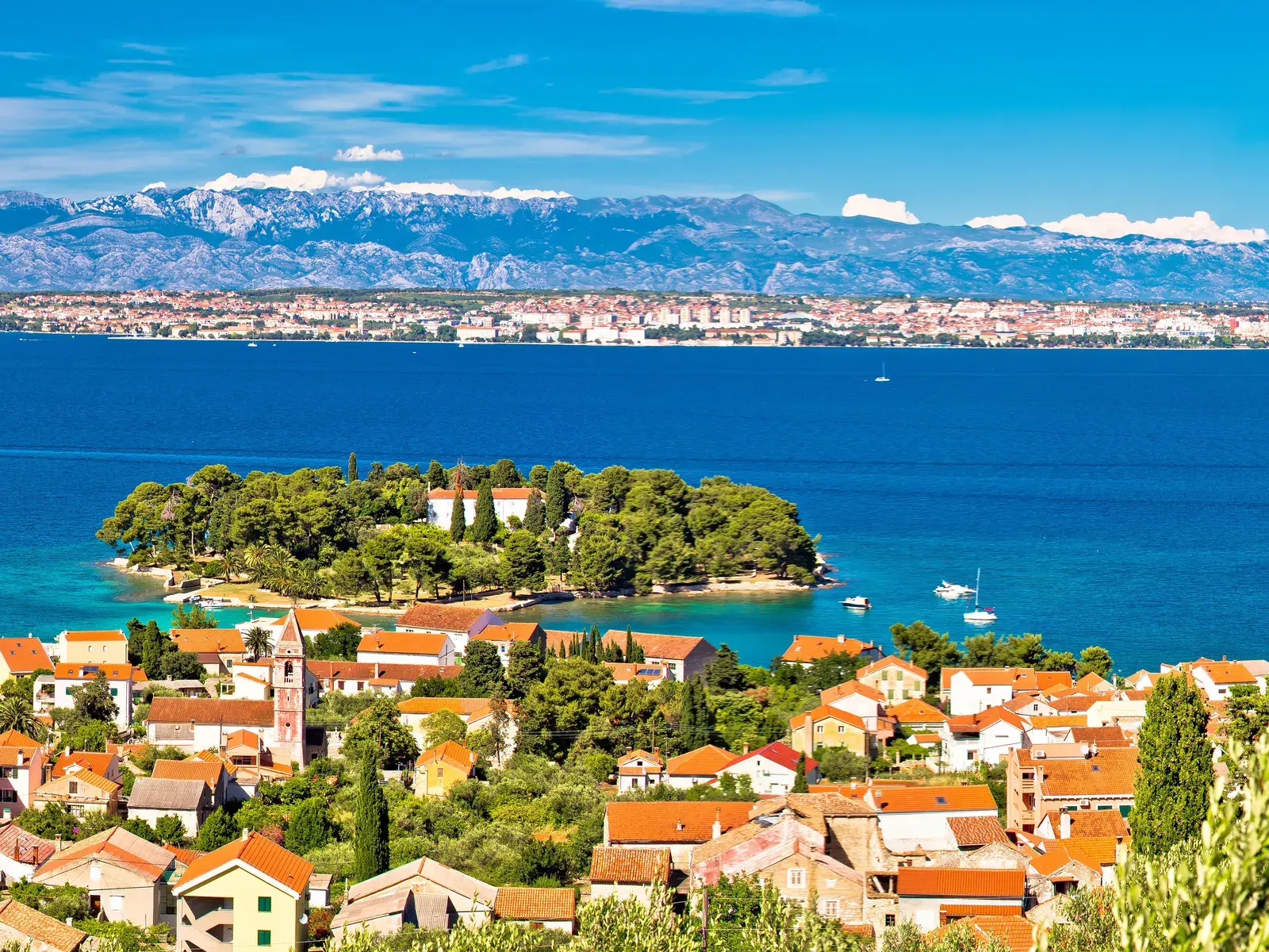 Malerischer Ausblick während einer Wanderung von der Insel Ugljan über die Adria auf die Küstenstadt Zadar und das Velebit-Gebirge.