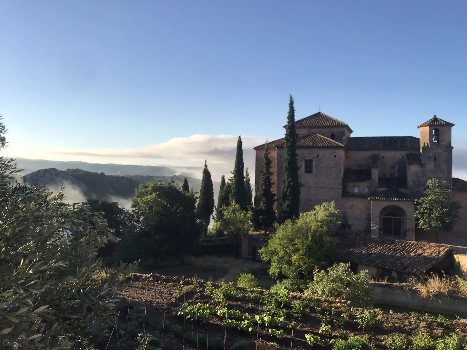 Morgensonne über der historischen Stiftskirche in Alquézar mit Blick auf die nebelverhangenen Täler der Sierra de Guara.