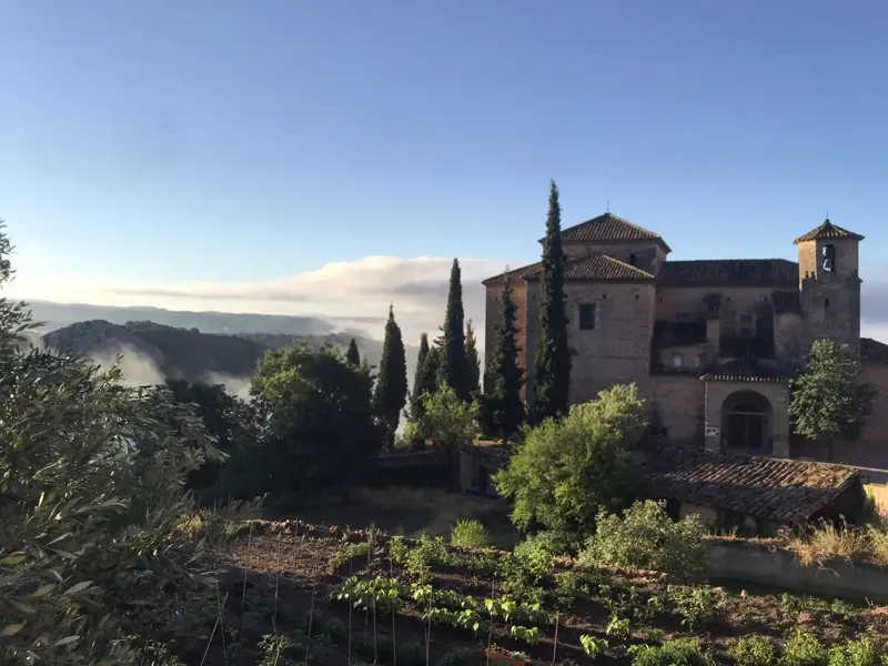 Morgensonne über der historischen Stiftskirche in Alquézar mit Blick auf die nebelverhangenen Täler der Sierra de Guara.