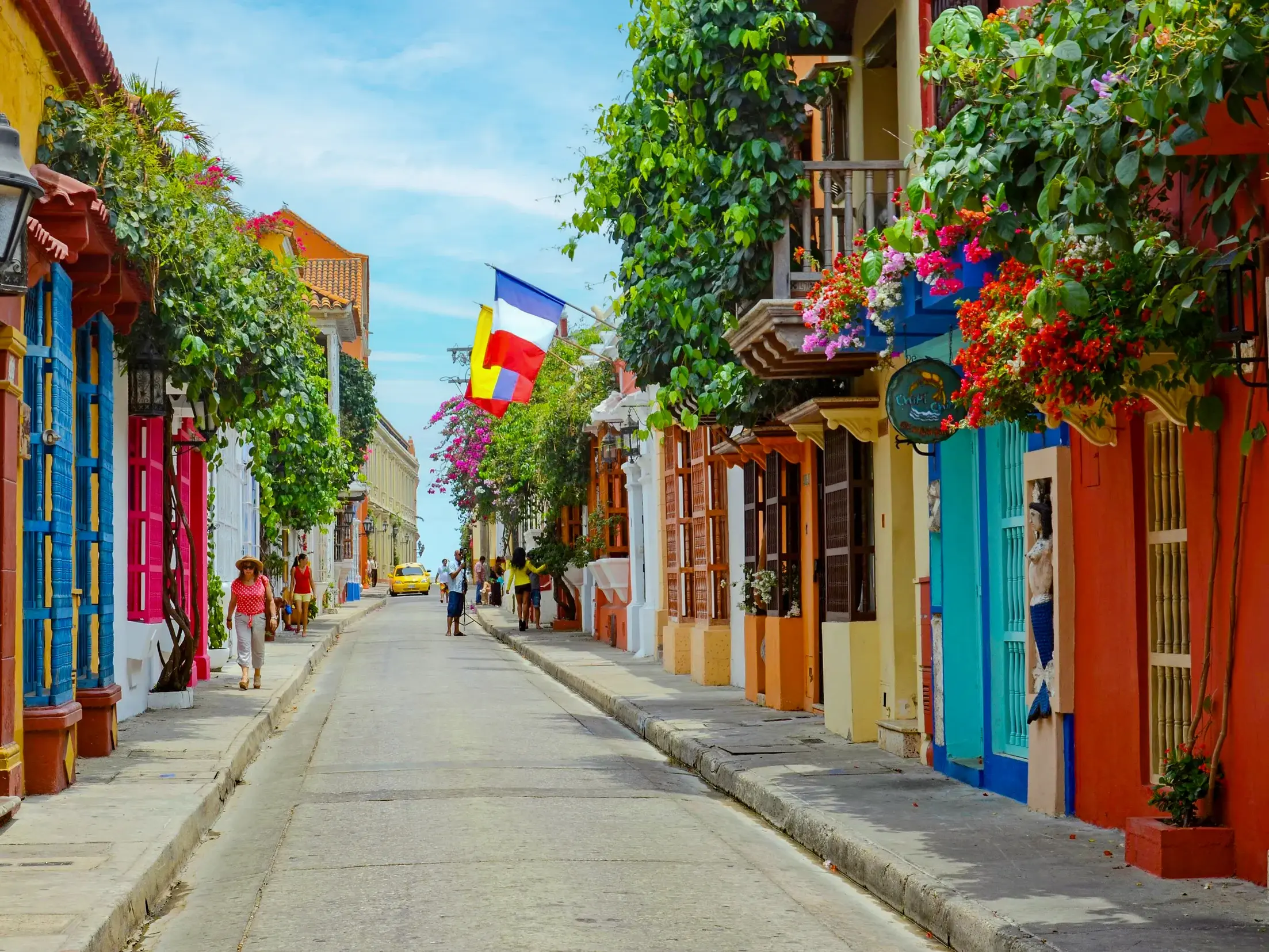 Eine farbenfrohe Gasse in der kolonialen Altstadt von Cartagena, gesäumt von bunten Häusern mit üppig bepflanzten Balkonen.