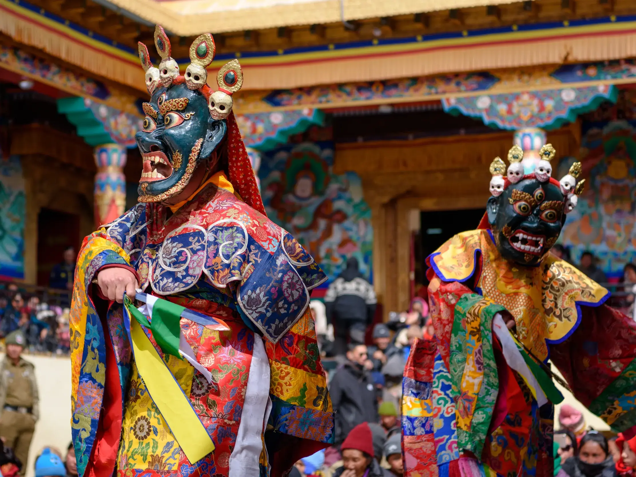 Zwei Tänzer in bunten Kostümen und Dämonenmasken beim traditionellen Maskentanz auf einem Klosterfest in Punakha, Bhutan.