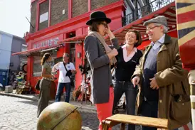 Studiosus-Reiseleiterin und Reisegruppe bei einem heiteren Moment vor einem roten Antiquitätenladen in London.
