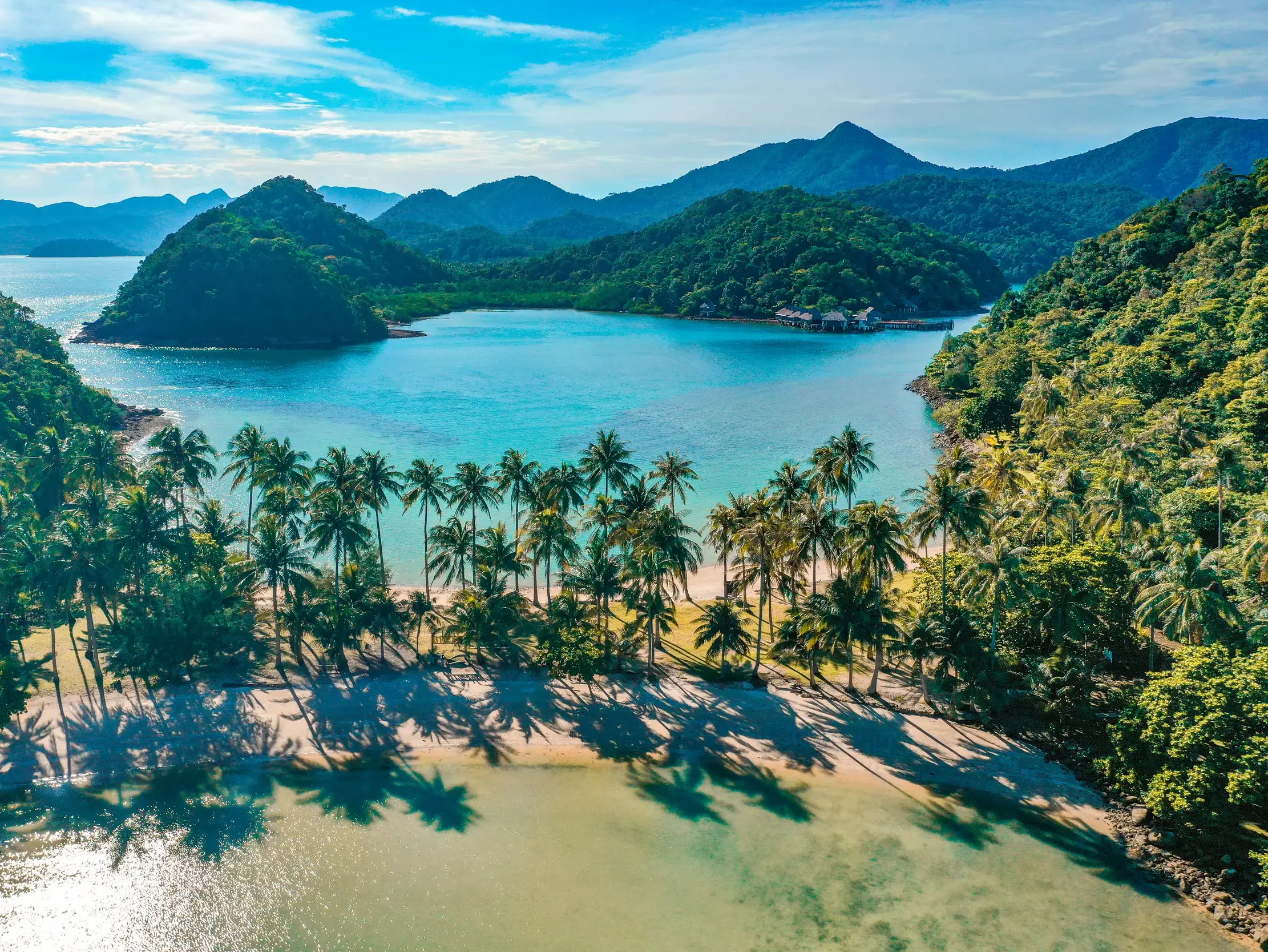 Paradiesische Bucht auf der Insel Phu Quoc in Vietnam: Sandstrand mit Palmen, türkises Meer und grüne Hügellandschaft.
