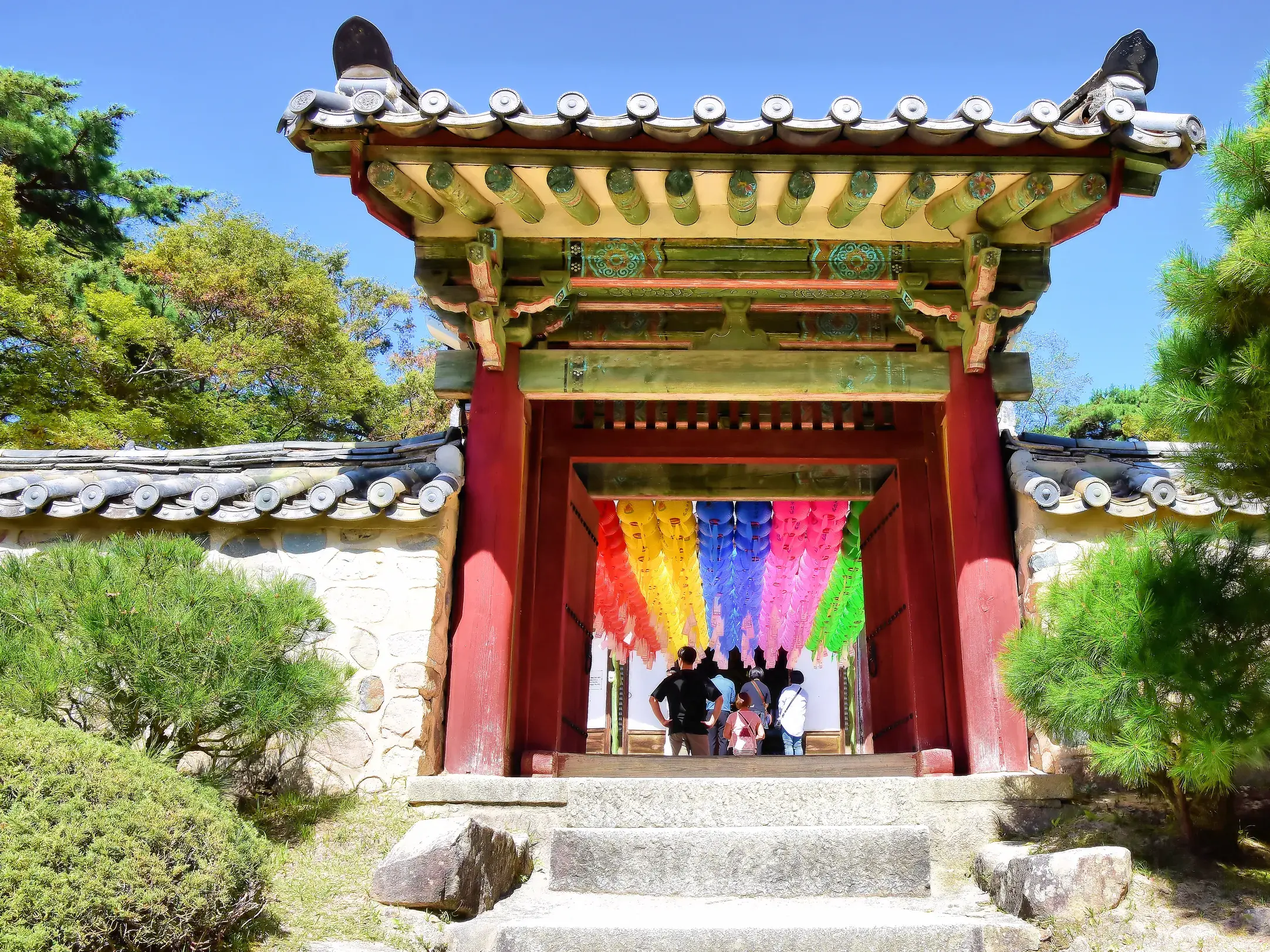 Reisegruppe unter bunten Laternen am traditionellen Eingangstor des Bulguksa-Tempels in Gyeongju, Südkorea.
