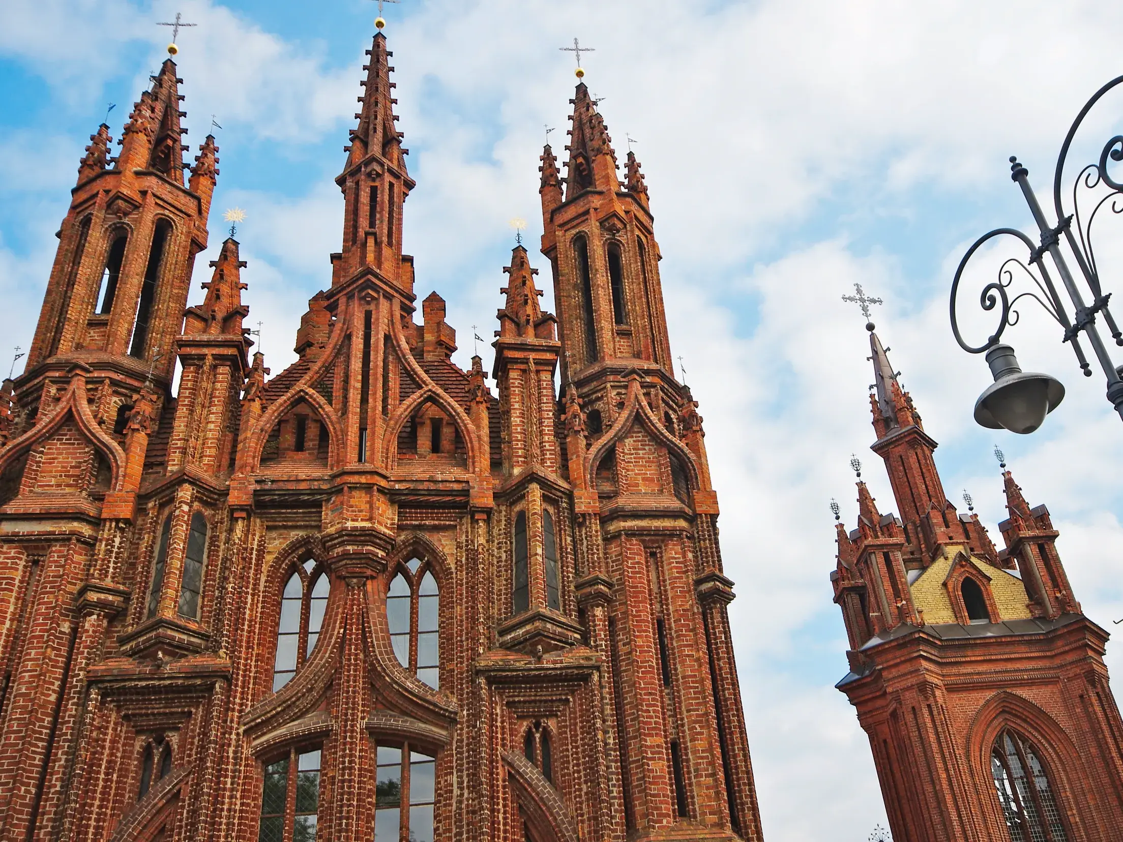 Die filigrane Backsteinfassade der gotischen St.-Annen-Kirche in Vilnius mit ihren spitzen Türmen unter bewölktem Himmel.