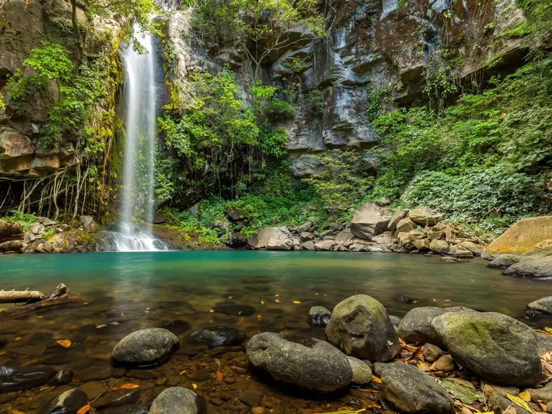 Der Nauyaca Wasserfall stürzt in ein klares, türkises Becken, das von dichtem Dschungel und Felsen in Costa Rica umgeben ist.