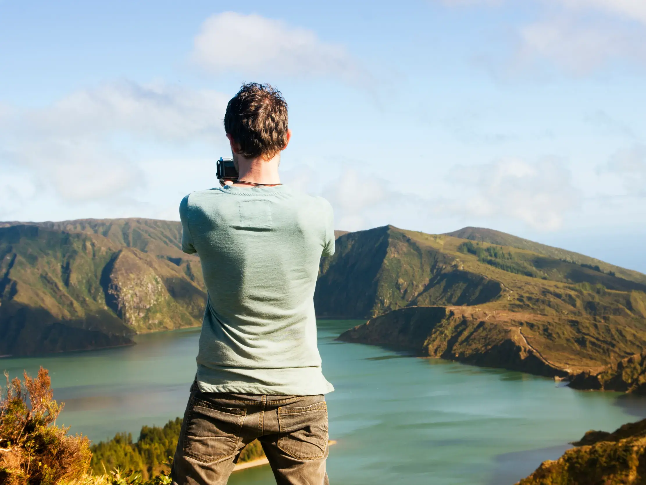 Ein Mann fotografiert auf seiner Rundreise den atemberaubenden Ausblick auf den Kratersee Lagoa do Fogo auf Sao Miguel.
