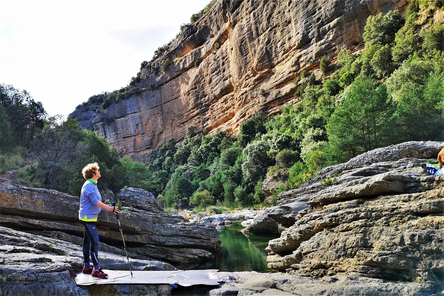 Eine Wanderin mit Trekkingstöcken bestaunt die imposante Felswand in der Schlucht des Río Verde in der Sierra de Guara.