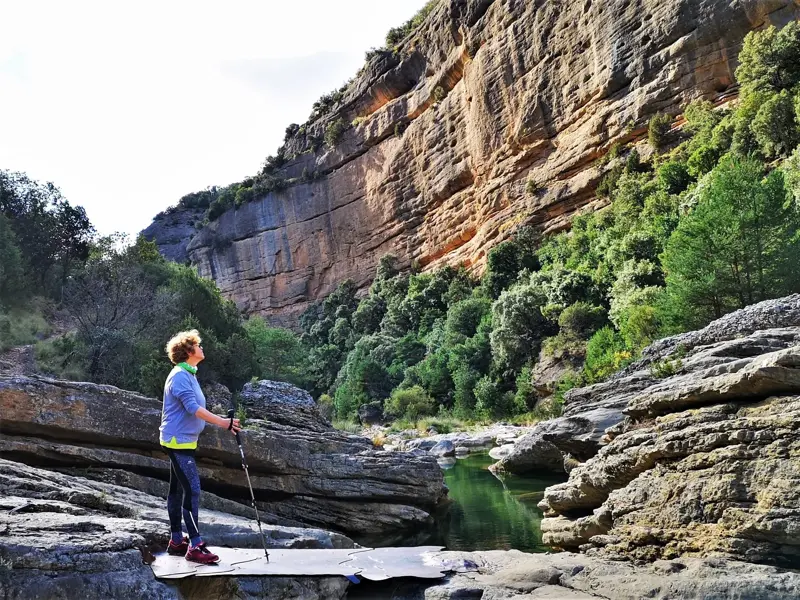 Eine Wanderin mit Trekkingstöcken bestaunt die imposante Felswand in der Schlucht des Río Verde in der Sierra de Guara.