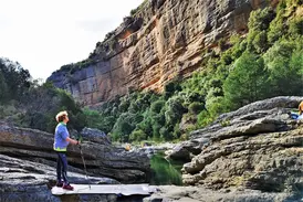 Eine Wanderin mit Trekkingstöcken bestaunt die imposante Felswand in der Schlucht des Río Verde in der Sierra de Guara.
