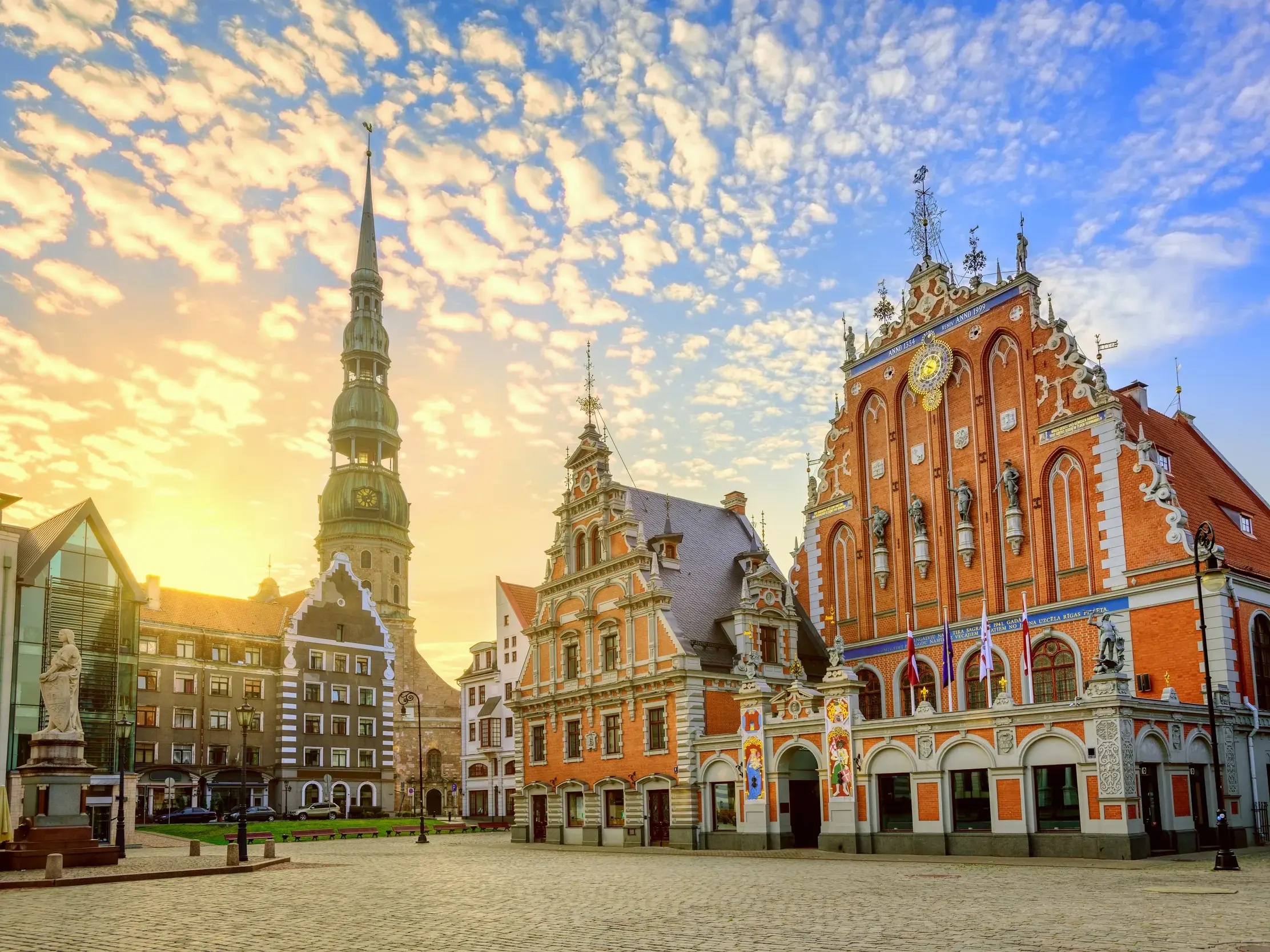 Das historische Schwarzhäupterhaus und die Petrikirche in der Altstadt von Riga im warmen Licht der aufgehenden Sonne.