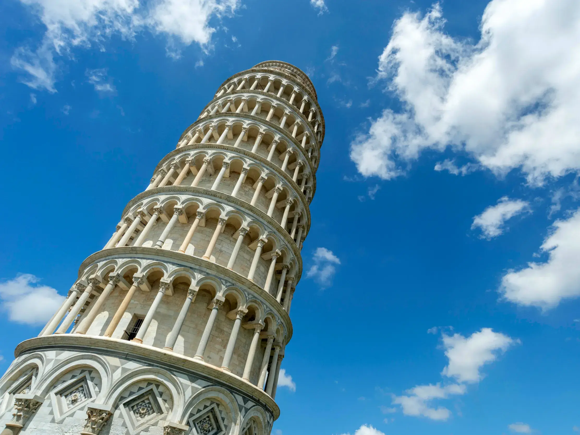 Der berühmte Schiefe Turm von Pisa in der Toskana, aufgenommen aus der Froschperspektive bei strahlend blauem Himmel.