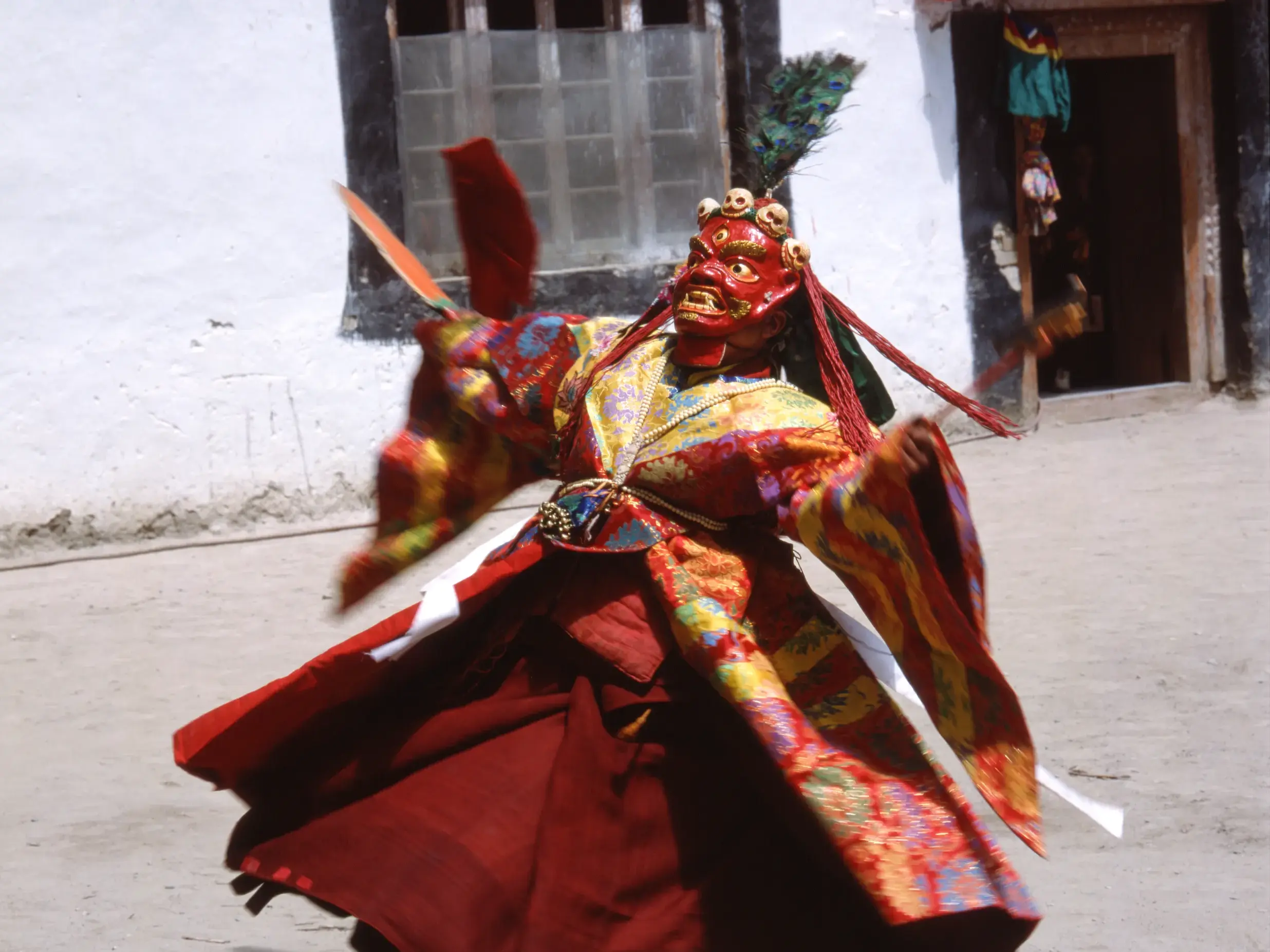 Ein Mönch mit roter Maske und in farbenprächtiger Tracht führt einen rituellen Tanz bei einem Klosterfest in Ladakh auf.