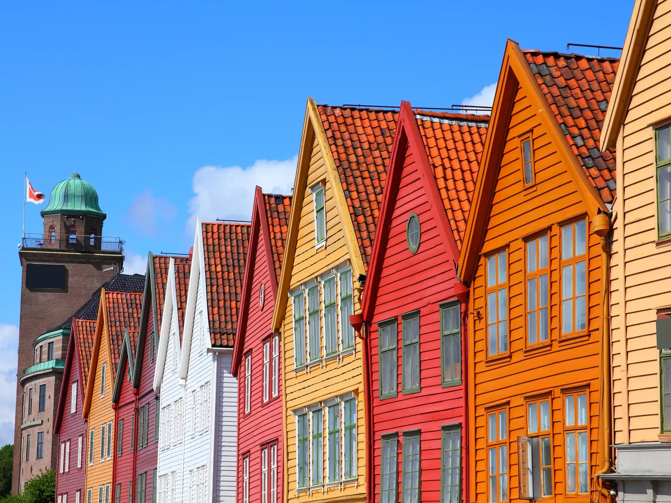 Die bunten Giebelfassaden des historischen Hanseviertels Bryggen in Bergen leuchten unter strahlend blauem Himmel.