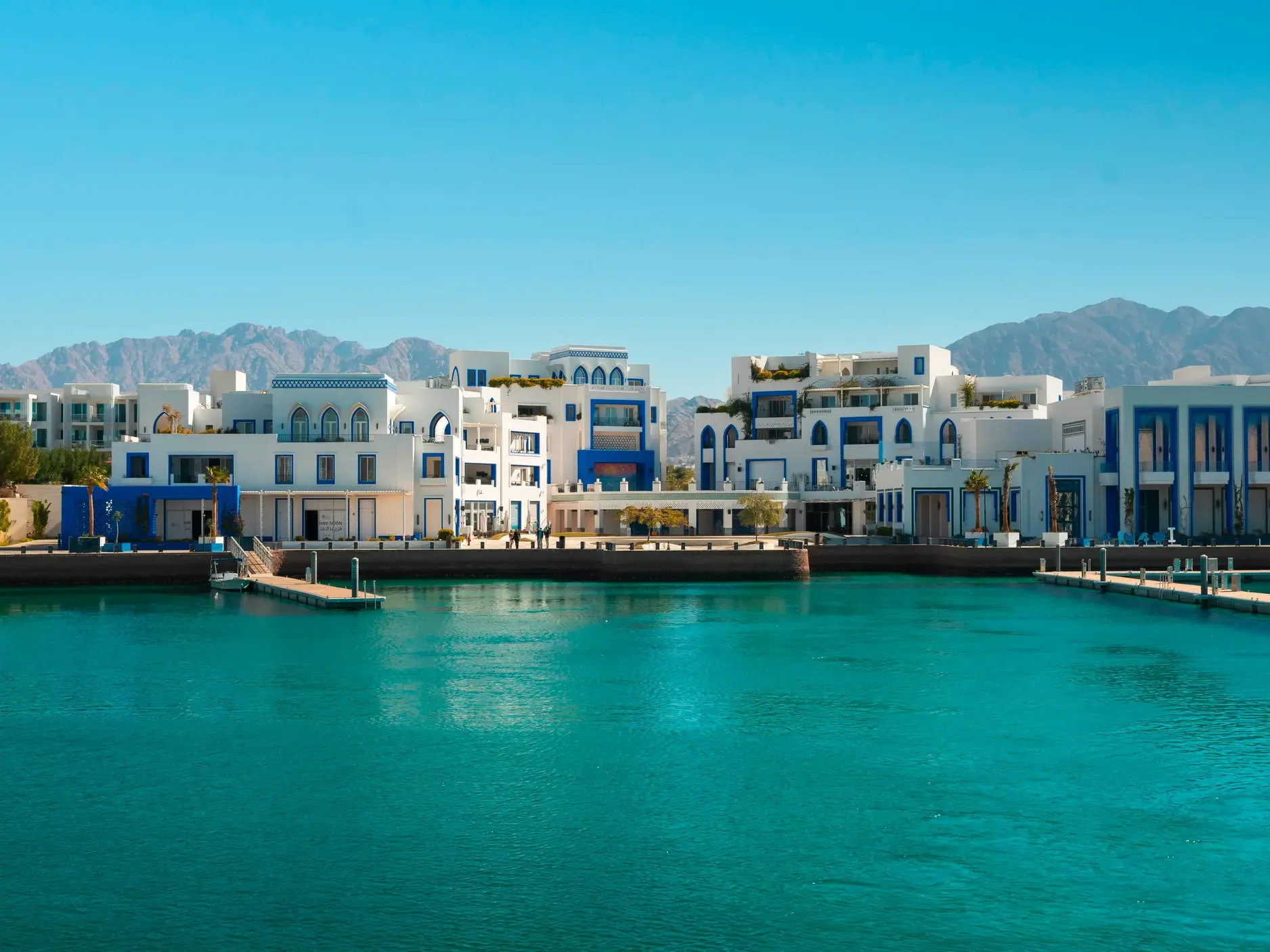 Moderne, weiß-blaue Architektur des Hotels Cloud 7 am türkis schimmernden Wasser des Yachthafens von Akaba in Jordanien.