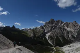 Zwei Wanderer auf einem schmalen Geröllpfad während einer Hüttenwanderung mit Blick auf die Felsgipfel der Sextener Dolomiten.