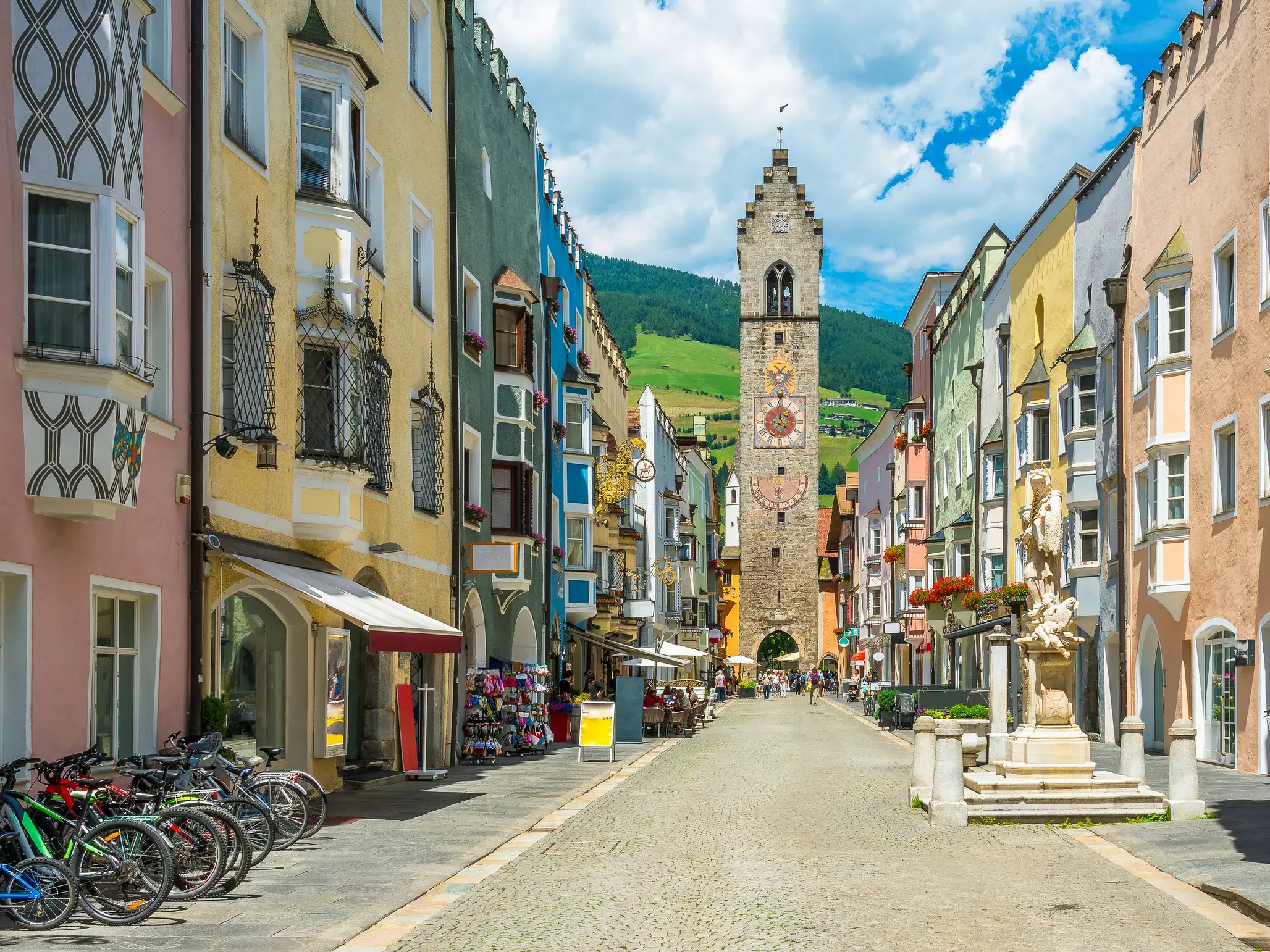 Gasse in der historischen Altstadt von Sterzing mit bunten Fassaden und dem markanten Zwölferturm am Ende der Straße.