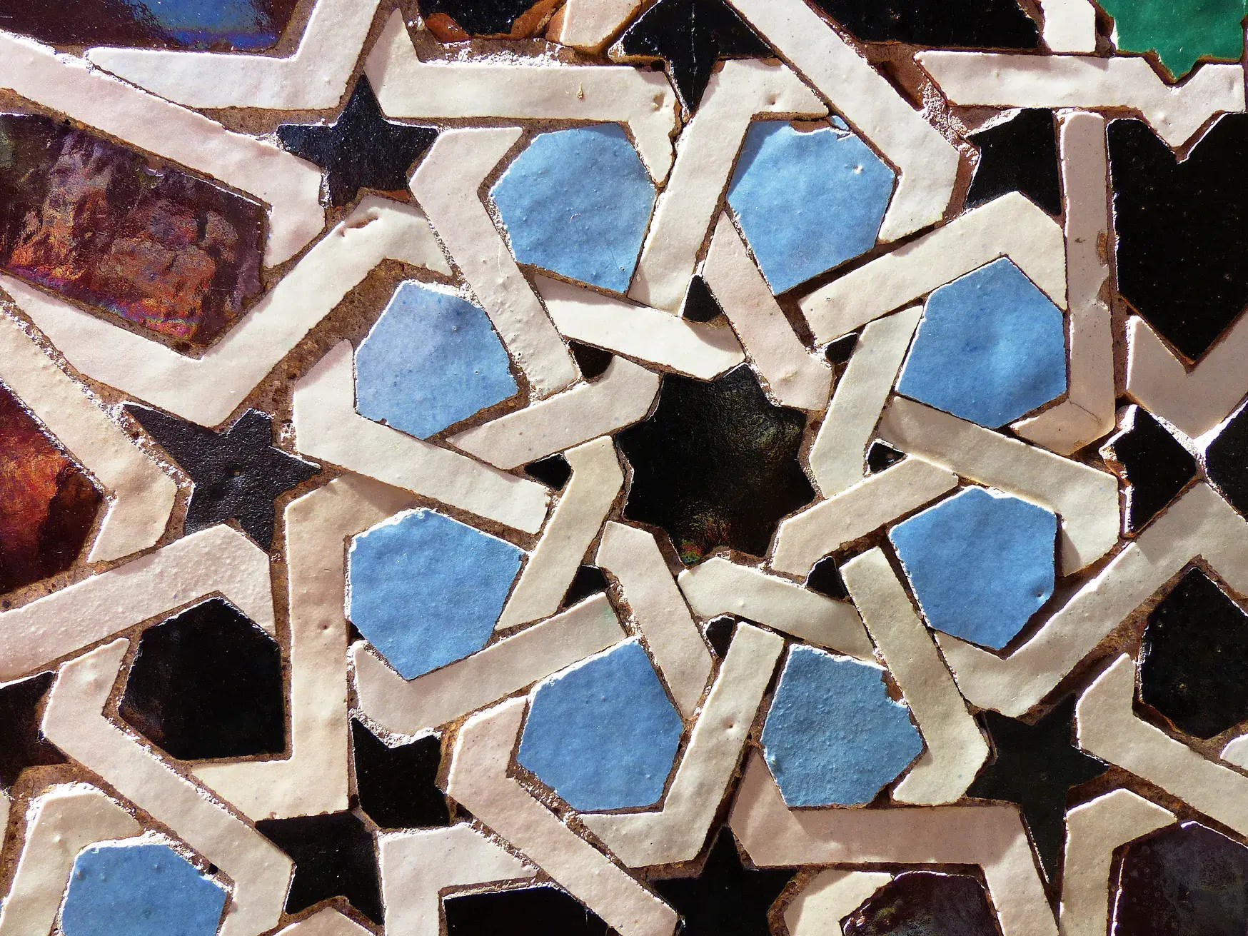Nahaufnahme der kunstvollen, handgefertigten Zellige-Mosaike mit geometrischen Mustern in der Medersa Ben Youssef in Marrakesch.