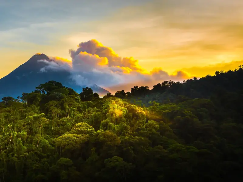 Wanderung mit Blick auf den Vulkan Arenal, dessen Gipfel bei Sonnenaufgang über den grünen Regenwald von Costa Rica ragt.