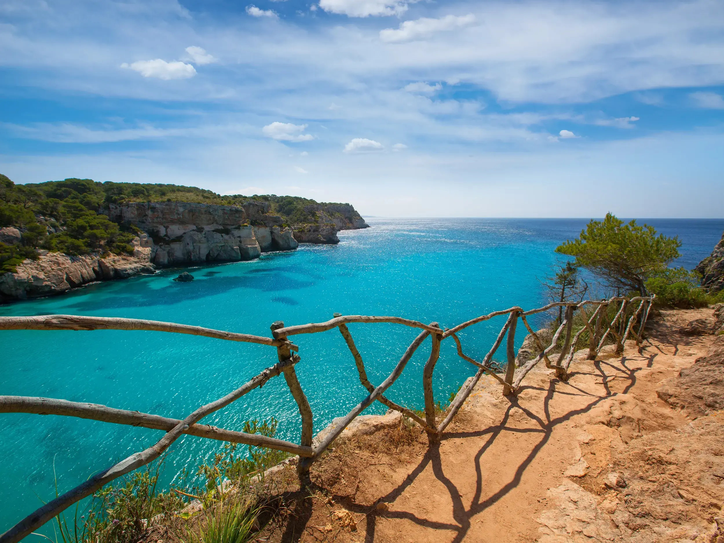Blick vom Wanderweg Camí de Cavalls über die Felsküste auf die türkisfarbene Bucht Cala Macarella auf der Insel Menorca.