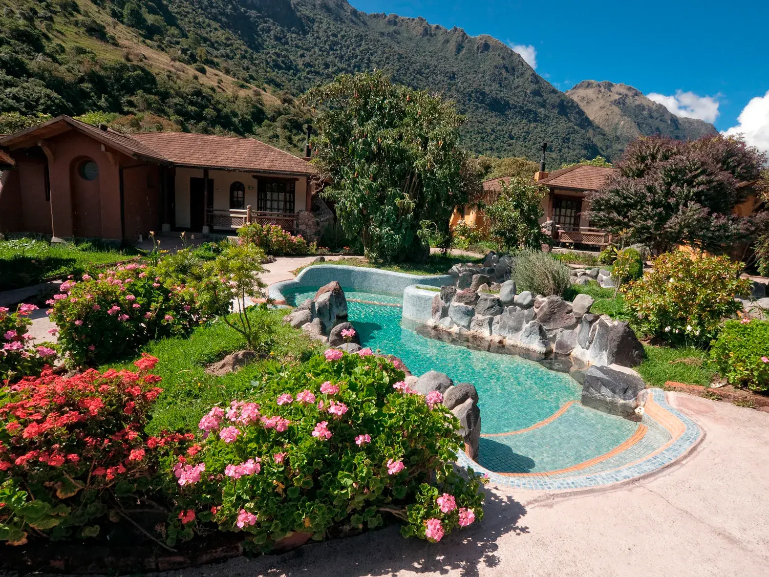 Ein geschwungenes Thermalbecken im Hotel Termas de Papallacta, umgeben von blühenden Gärten vor der Bergkulisse der Anden.